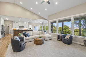 Living room with ceiling fan, high vaulted ceiling, recessed lighting, and light wood-style floors