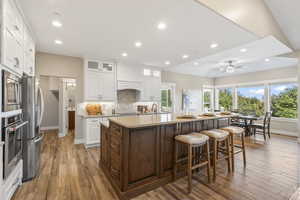 Kitchen with appliances with stainless steel finishes, a kitchen island with sink, white cabinets, and recessed lighting