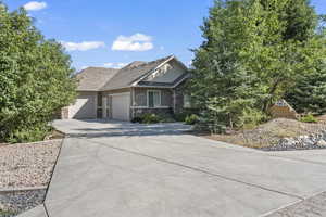 View of front of house featuring stone siding, a garage, and concrete driveway