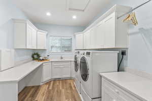 Laundry room with independent washer and dryer, cabinet space, light wood-type flooring, and recessed lighting