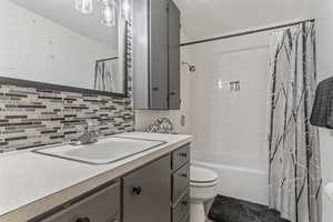 Full bath with vanity, shower / tub combo with curtain, and tasteful backsplash