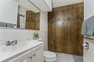 Full bath with tile walls, vanity, a textured ceiling, tile patterned floors, and curtained shower