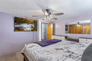 Carpeted bedroom featuring a textured ceiling and a ceiling fan