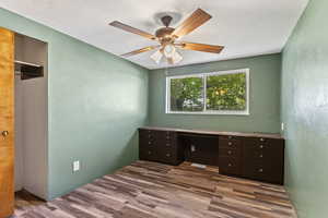 Unfurnished office with a textured wall, a ceiling fan, and wood finished floors