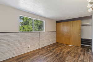 Unfurnished bedroom featuring wood finished floors, a closet, wainscoting, and wooden walls