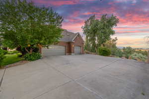 View of front facade with driveway, brick siding, and an attached garage