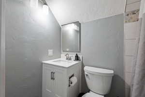 Bathroom featuring a textured wall, vanity, and a textured ceiling