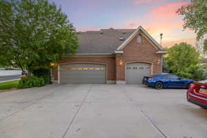 Traditional-style home with driveway, brick siding, a garage, and a shingled roof