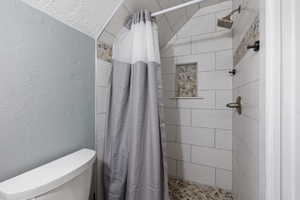 Bathroom with tiled shower and a textured wall