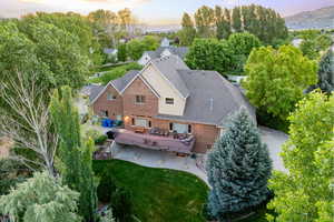 Back of house with brick siding, a patio area, a mountain view, a lawn, and roof with shingles