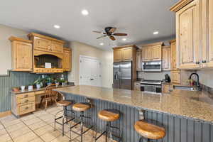 Kitchen featuring stainless steel appliances, a peninsula, ceiling fan, recessed lighting, and stone countertops