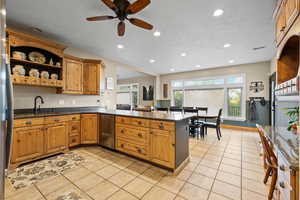 Kitchen featuring dishwasher, recessed lighting, light tile flooring, a peninsula, and healthy amount of natural light
