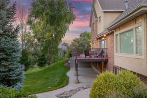 View of grassy yard featuring a patio area and a wooden deck