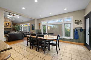 Dining room with healthy amount of natural light, light tile floors, recessed lighting, a stone fireplace, and lofted ceiling