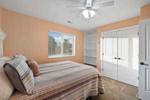 Bedroom with light carpet, a ceiling fan, and a closet