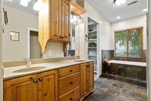 Bathroom with double vanity, a bath, and stone floors