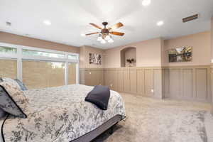 Bedroom featuring a wainscoted wall, recessed lighting, carpet, a decorative wall, and ceiling fan