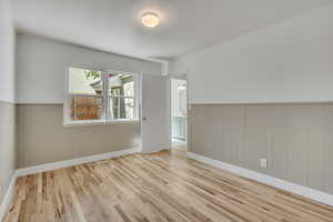 Third bedroom featuring single hung double pane window, hard wood finished floors and wainscoted walls with walk-in closet.
