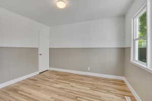 Third bedroom featuring single hung double pane window, hard wood finished floors and wainscoted walls with walk-in closet.