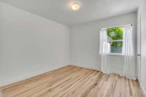 Second bedroom featuring single hung double pane window, hard wood finished floors and baseboards with walk-in closet.