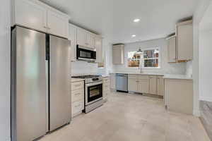 Open Remodeled Kitchen featuring all new custom cabinetry, new Quartz stone countertops and large tile floors, stainless appliances, 5 burner gas range, stainless steel door top control dishwasher, refrigerator with freezer and microwave.