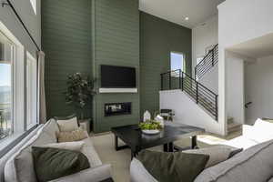 Living area with a high ceiling, stairway, a glass covered fireplace, wooden walls, and recessed lighting