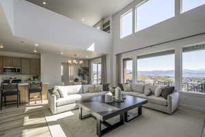 Living area with a chandelier, healthy amount of natural light, recessed lighting, a mountain view, and a towering ceiling