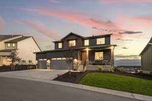 View of front of house with a porch, driveway, board and batten siding, a yard, and stone siding