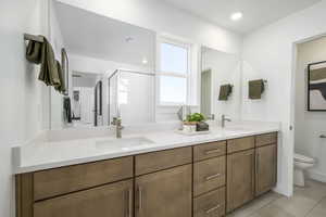 Full bath with double vanity, a stall shower, and tile patterned floors