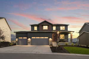 View of front facade with driveway, board and batten siding, covered porch, stone siding, and a garage