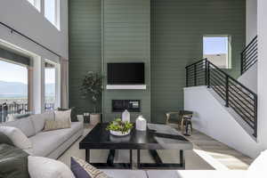 Living room with a towering ceiling, wood finished floors, a mountain view, stairway, and a large fireplace