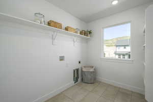 Laundry room with hookup for an electric dryer, hookup for a washing machine, and light tile patterned flooring