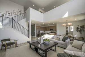 Living area featuring a chandelier, stairway, light wood-style flooring, recessed lighting, and a high ceiling