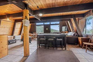 Tiled dining space featuring a wood ceiling with exposed beams and wood walls