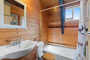 Bathroom featuring wooden walls, vanity, shower / tub combo, and wood ceiling