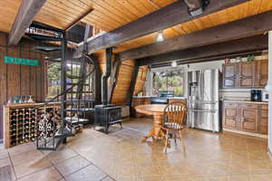 Dining room with a wood stove, a wood ceiling with exposed beams, and wood walls