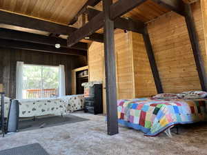 Bedroom with wooden walls, carpet, and a wooden ceiling with exposed beams
