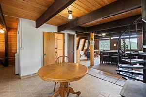 Dining space featuring a wood ceiling with exposed beams, wooden walls, and light tile patterned floors