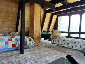 Carpeted bedroom featuring wooden ceiling and wood walls