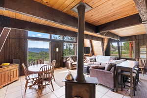 Living area with wooden ceiling, light tile patterned floors, wood walls, and decorative columns