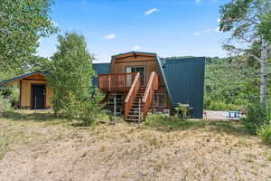 Back of house featuring a deck, stairs, a metal roof, and an outdoor structure