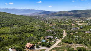 Aerial view of property's location with a mountainous background and a heavily wooded area