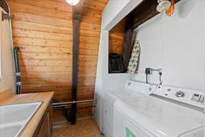 Washroom featuring washing machine and dryer, wood walls, and tile patterned flooring