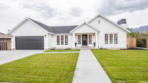 Modern farmhouse featuring a garage, concrete driveway, a porch, a chimney, and a mountain view