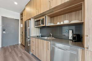 Kitchen featuring stainless steel appliances, open shelves, modern cabinets, and light brown cabinets