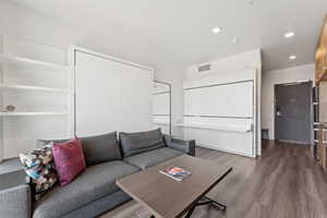 Living area with dark wood-type flooring and recessed lighting