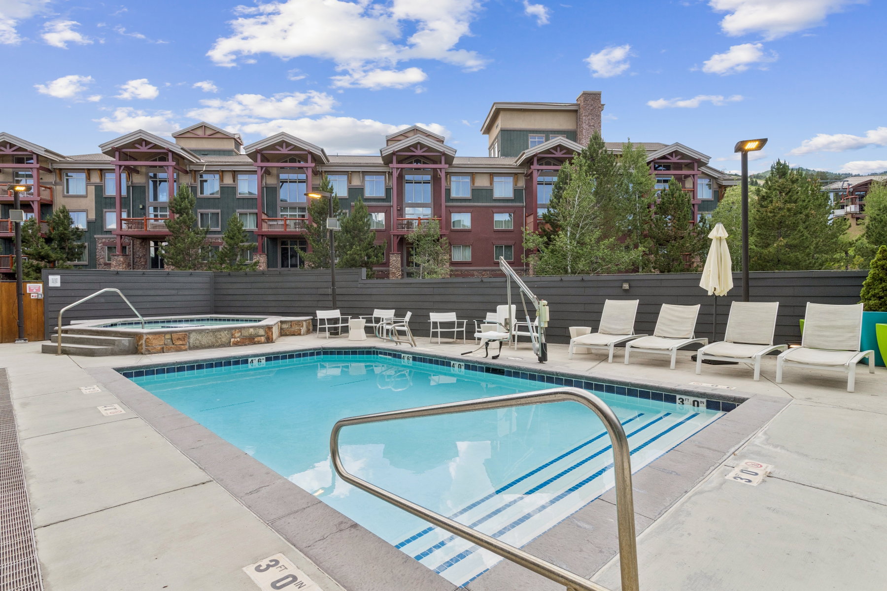 Community pool with a hot tub, a patio, and a residential view