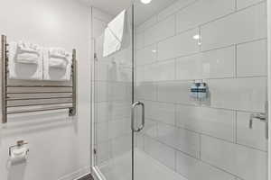Full bath featuring radiator heating unit, a shower stall, and a towel warmer