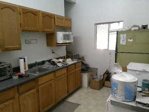 Kitchen with brown cabinets, freestanding refrigerator, white microwave, and dark countertops