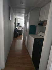 Laundry area with separate washer and dryer, wood finished floors, and cabinet space